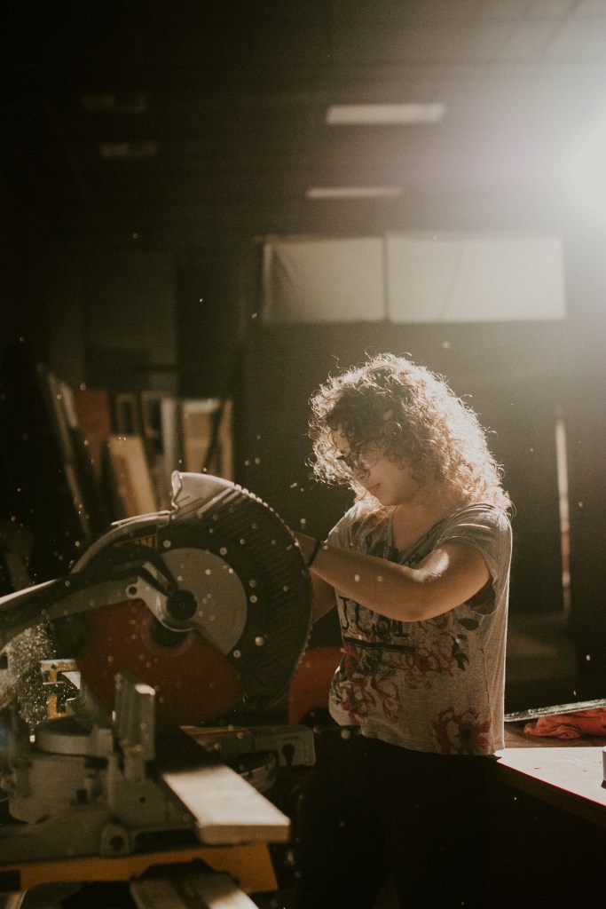 Nicole cutting a plank of wood for a set piece